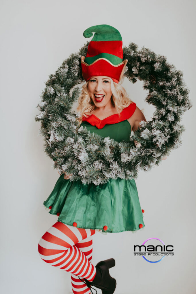 Fun Christmas elf smiling and playing around with a wreath for photos