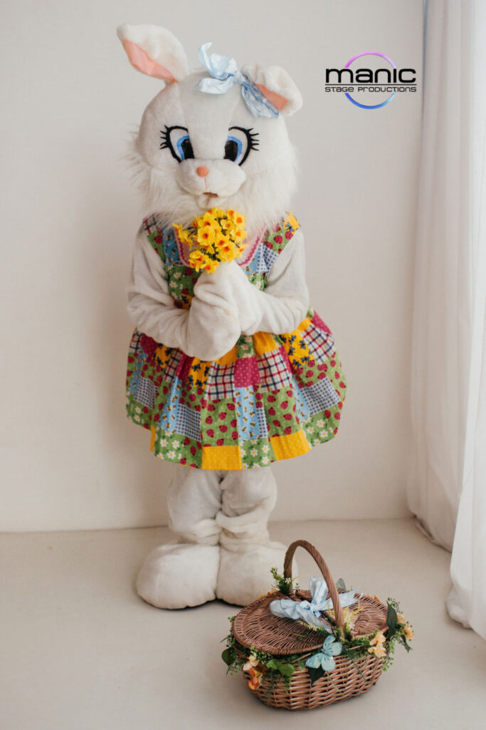 Easter bunny character mascot holding yellow daffodils and looking fun and fancy in a flowery dress